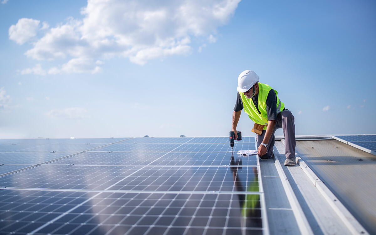 Ein Bauarbeiter auf einem Dach mit Photovoltaik-Anlage