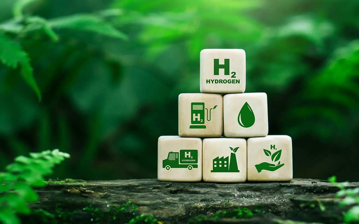 Gestapelte kleine Holzwürfel mit symbolischen Darstellungen für grünen Wasserstoff