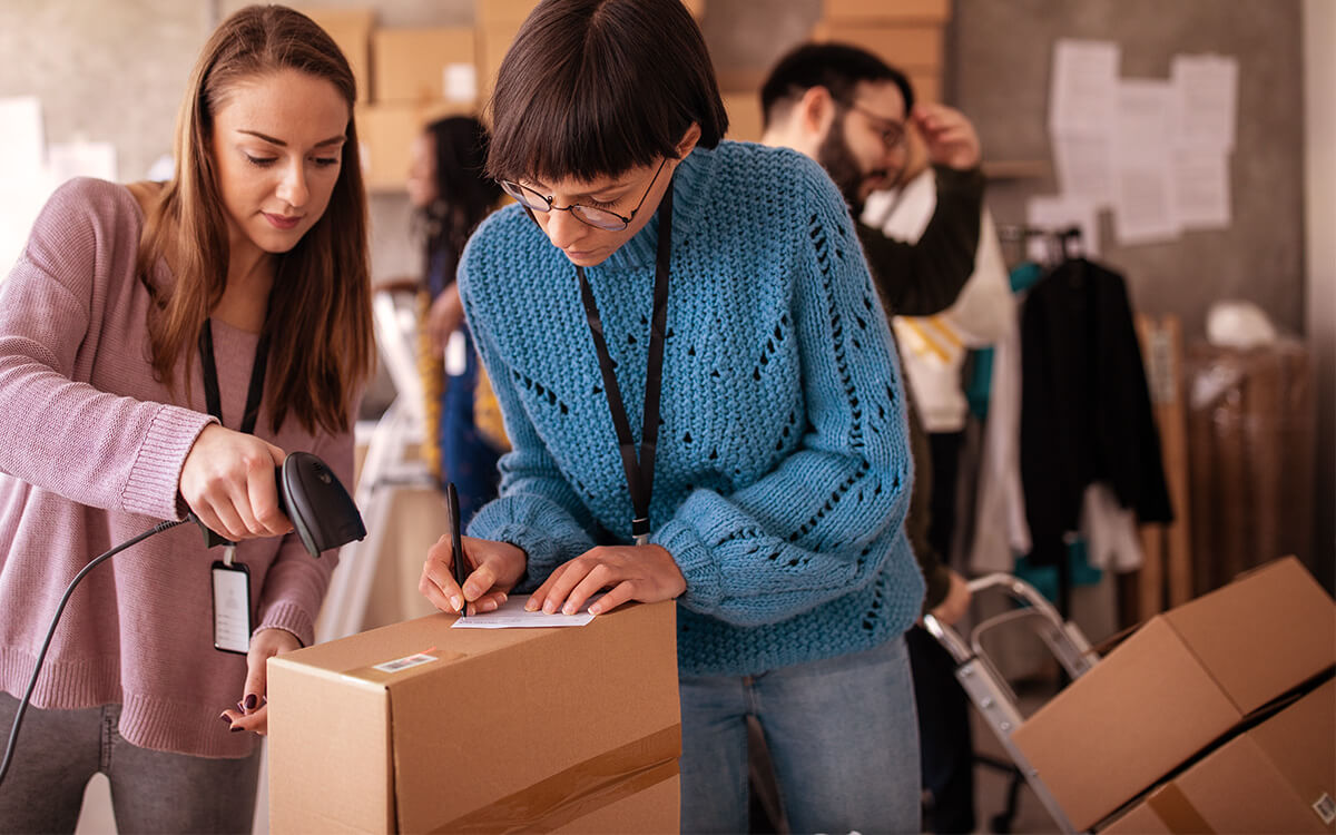 Zwei Frauen verpacken und scannen ein Paket