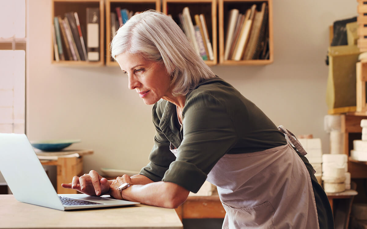 Frau bedient ihren Laptop am Schreibtisch stehend