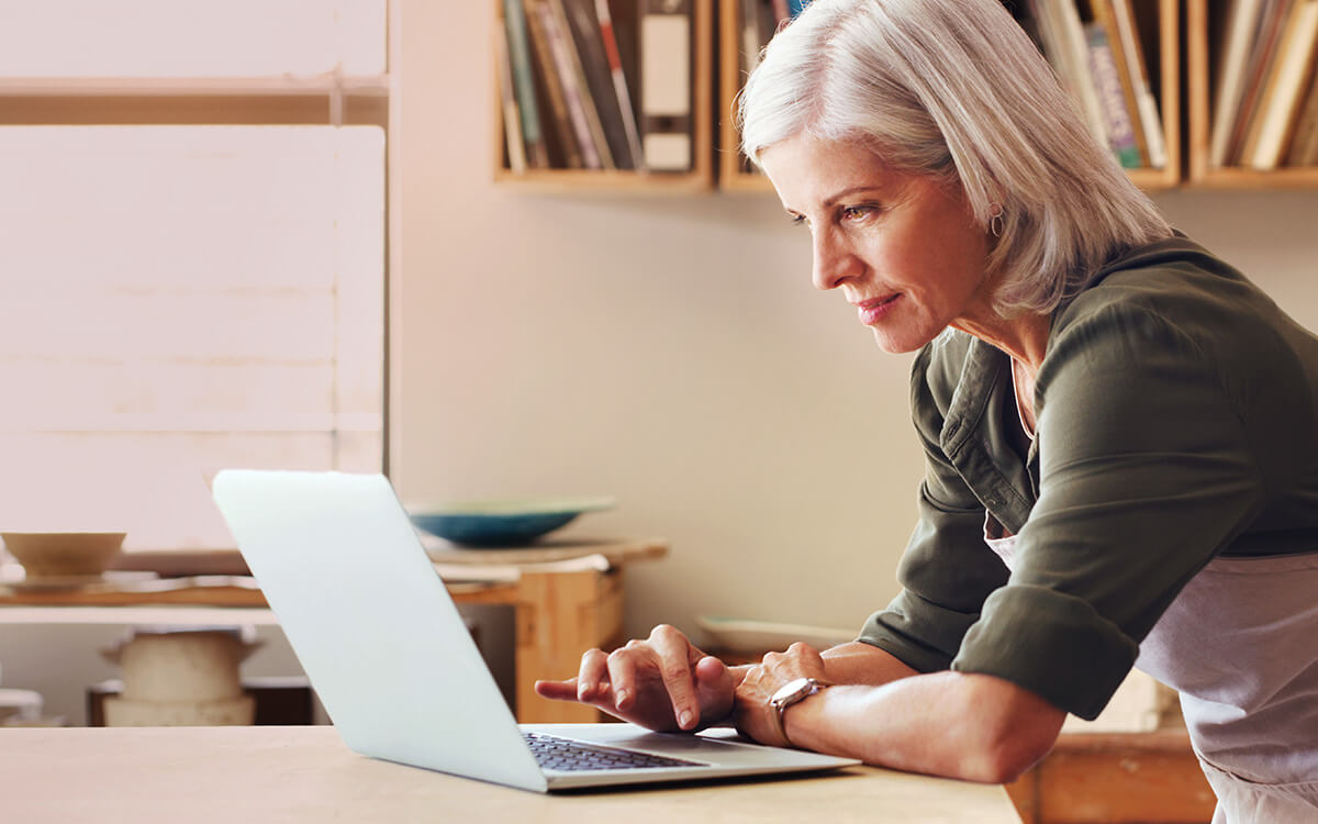 Eine Frau bedient ihren Laptop am Schreibtisch stehend