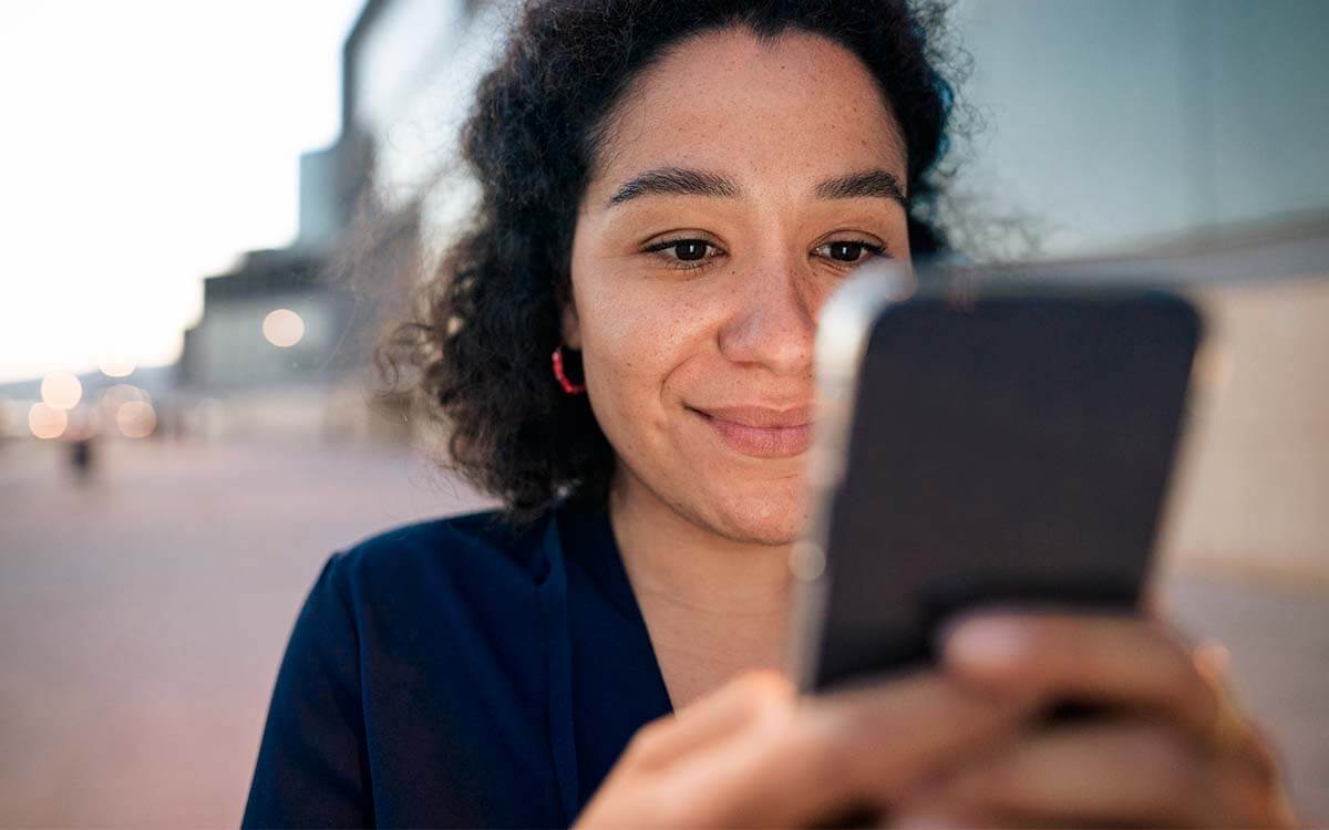 Eine glückliche Frau schaut auf eine Handy