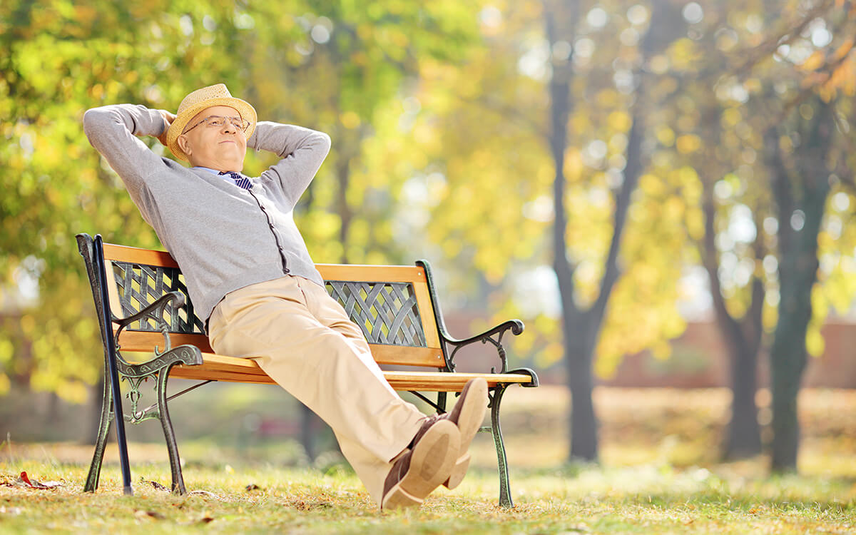 Mann genießt die Sonne im Park auf einer Bank sitzend