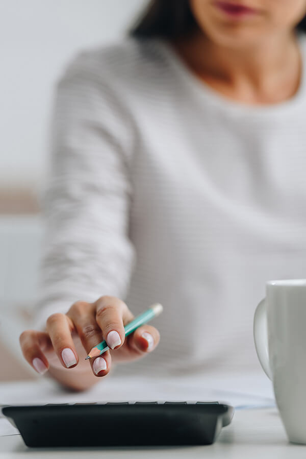 Frau mit Bleistift in der Hand bedient einen Taschenrechner