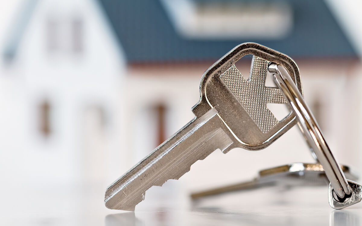 Ein Symbolbild: Haustürschlüssel vor einem Einfamilienhaus