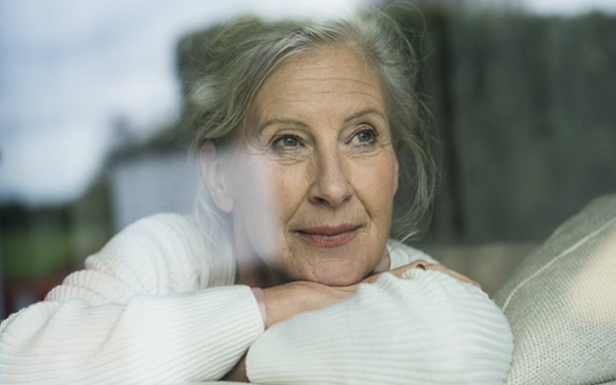 Ältere Dame sieht aus dem Fenster