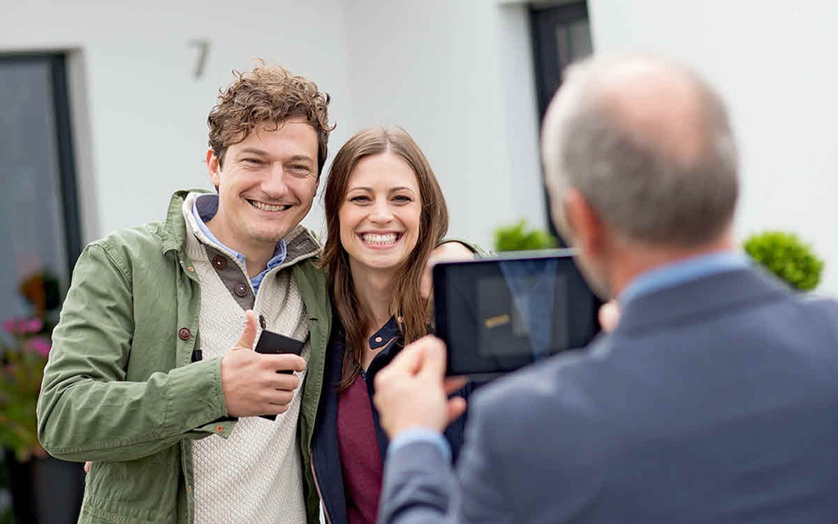 Junges Paar wird vor dem Haus fotografiert